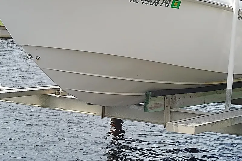 Slide: The Image of 2008 Everglades 210CC boat on lift over water, showcasing hull design. - 8