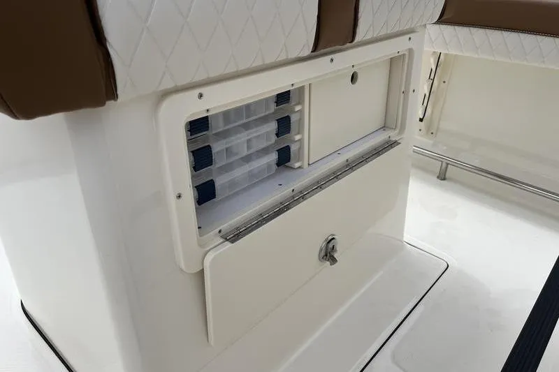 Slide: The Image of 2025 Pioneer 202 Sportfish boat storage compartment with tackle boxes and cushioned seating. - 15