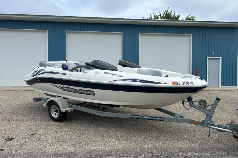 Slide: The Image of 2003 Sea Doo Challenger 2000 boat on trailer, parked outside blue garage. - 2