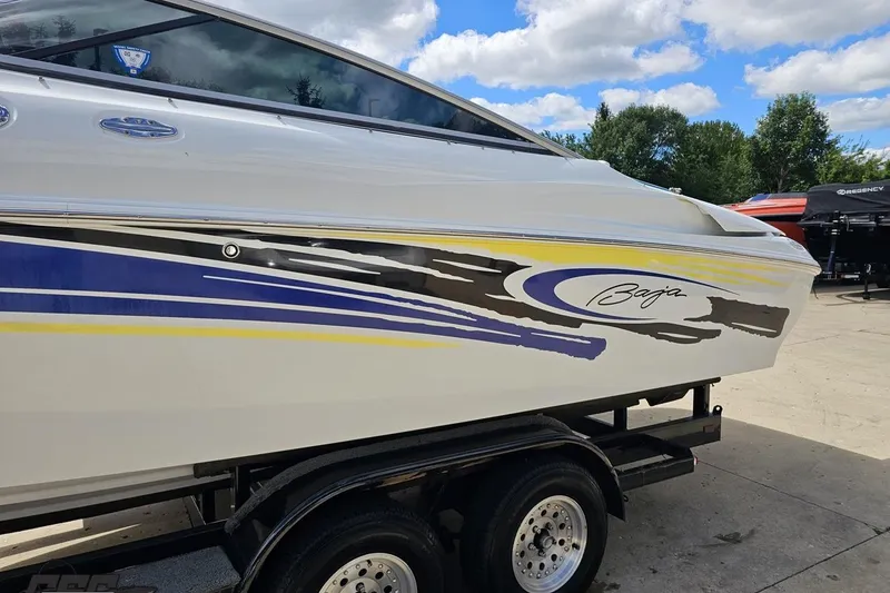 Slide: The Image of 2005 Baja 275 boat with colorful graphics on a trailer, under a blue sky. - 22