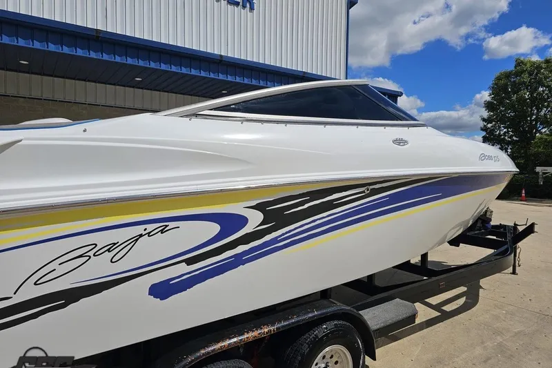 Slide: The Image of 2005 Baja 275 boat with colorful graphics on a trailer, parked outdoors. - 8