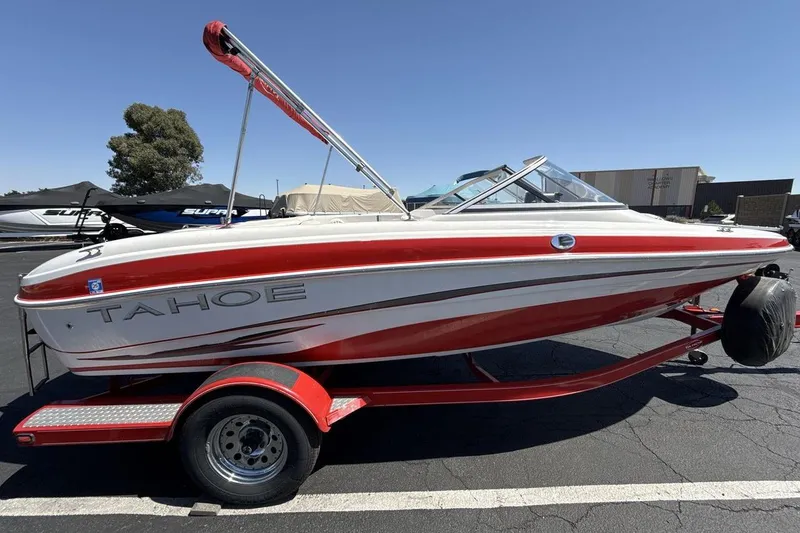 Slide: The Image of 2008 Tahoe Q5i SF boat on trailer, red and white design, parked outdoors. - 6