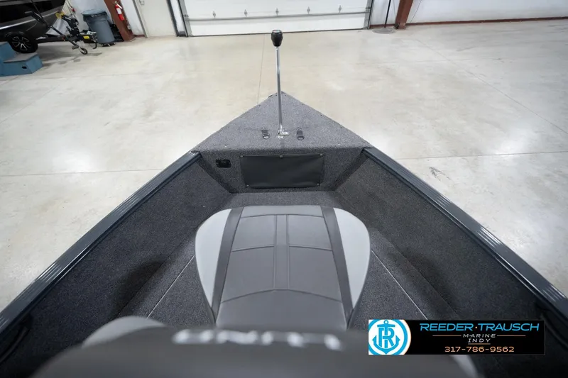 Slide: The Image of 2026 Lund 1650 Rebel XL Sport boat interior, featuring seating and control area in a showroom. - 16