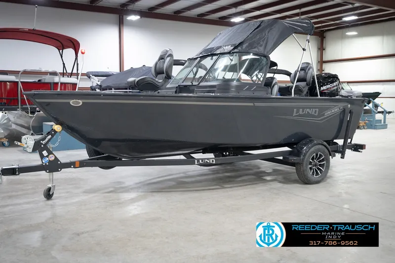 Slide: The Image of 2026 Lund 1650 Rebel XL Sport boat in showroom with trailer and canopy. - 2