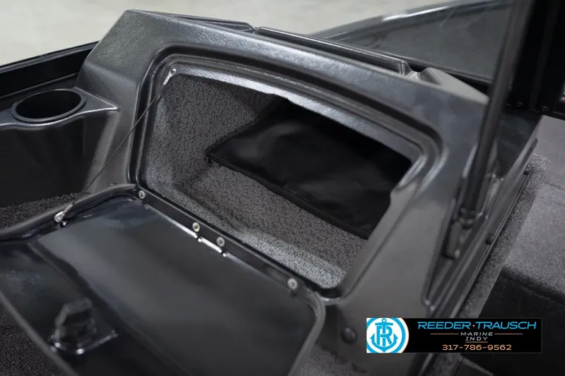 Slide: The Image of 2026 Lund 1650 Rebel XL Sport boat storage compartment with open lid and cup holder. - 27