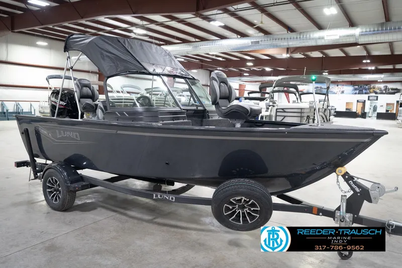Slide: The Image of 2026 Lund 1650 Rebel XL Sport boat in showroom, on trailer, with canopy and seating. - 4
