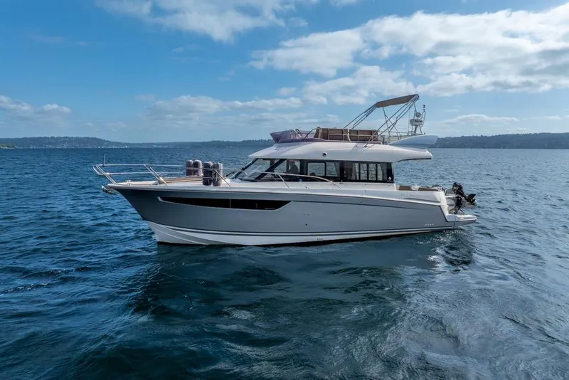 Slide: The Image of 2016 Jeanneau Velasco 43F yacht cruising on open water under a clear blue sky. - 2
