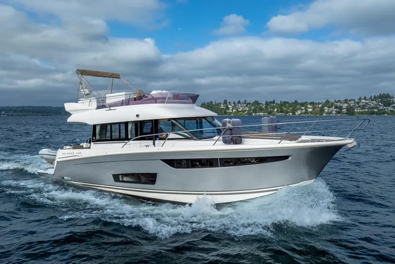 Slide: The Image of 2016 Jeanneau Velasco 43F yacht cruising on open water under a cloudy sky. - 56