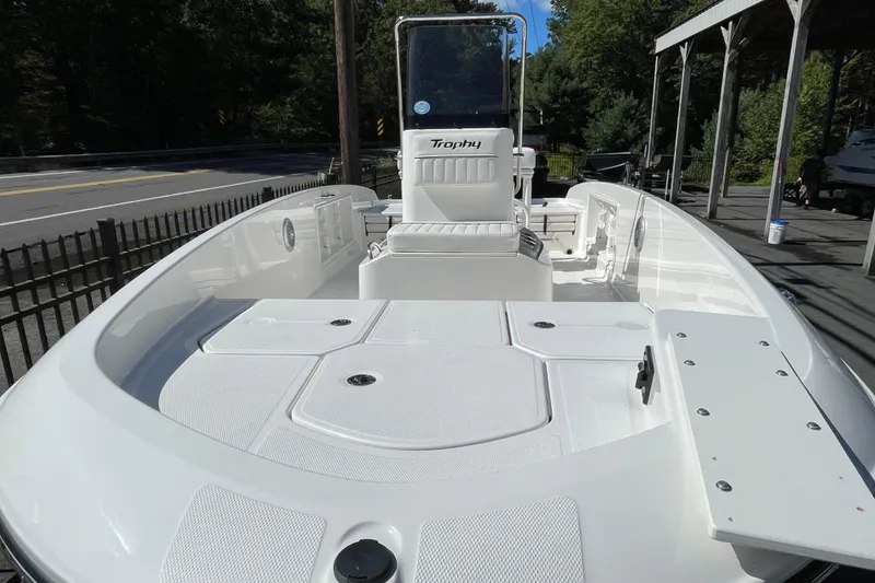 Slide: The Image of 2025 Bayliner Trophy T18 boat with spacious deck and seating, parked outdoors. - 1