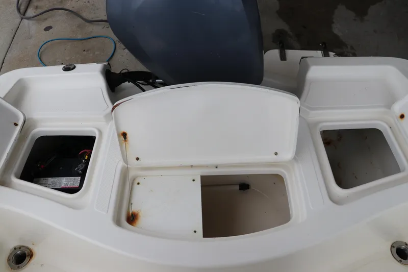 Slide: The Image of 2004 Pioneer 175 Bay Sport boat interior with storage compartments and visible rust. - 10