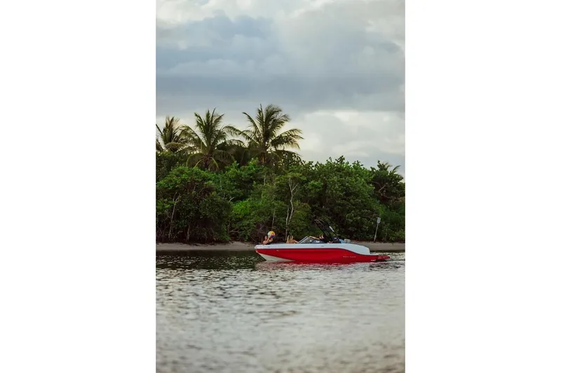 Slide: The Image of 2024 Bayliner DX 2050 boat cruising near lush tropical shoreline. - 8