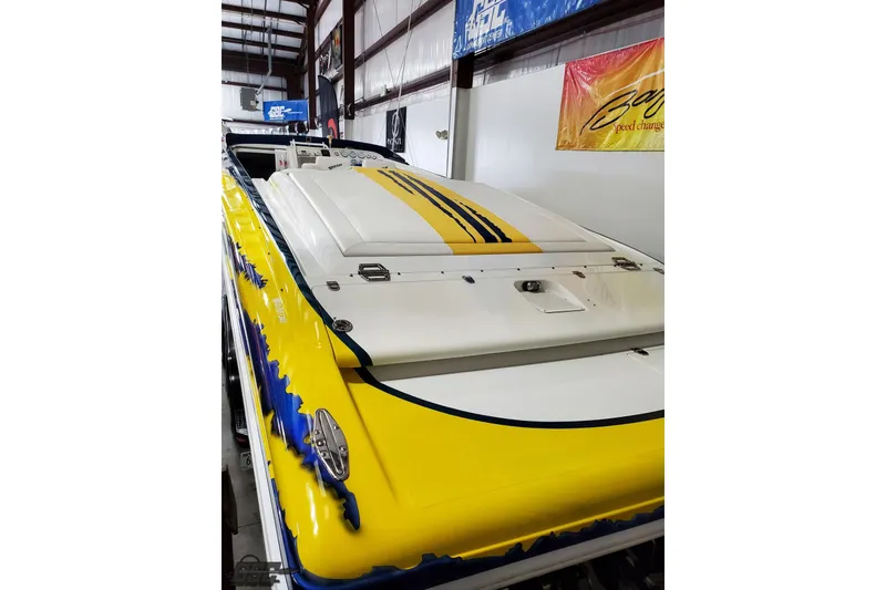 Slide: The Image of 2001 Hustler 50 Monster boat with vibrant yellow and blue design in a storage facility. - 10