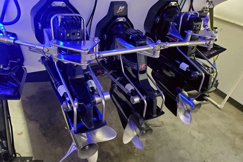 Slide: The Image of Triple outboard motors on a 2001 Hustler 50 Monster boat, illuminated in blue light. - 12