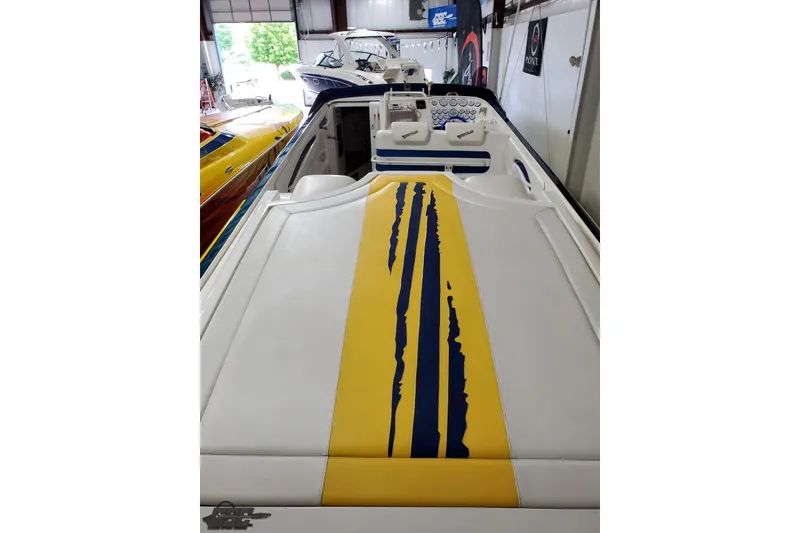 Slide: The Image of 2001 Hustler 50 Monster boat with yellow and blue stripe design in a showroom. - 14