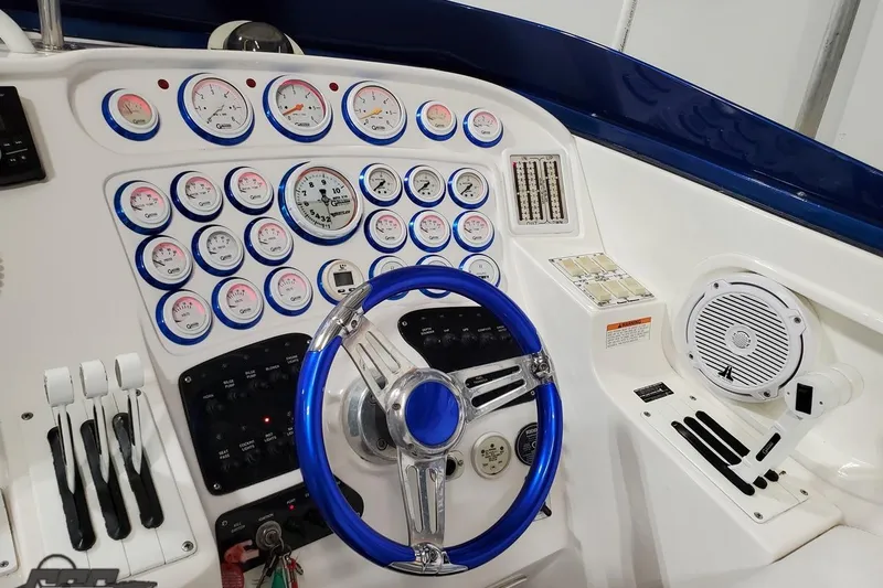 Slide: The Image of Dashboard of a 2001 Hustler 50 Monster boat with gauges and blue steering wheel. - 21