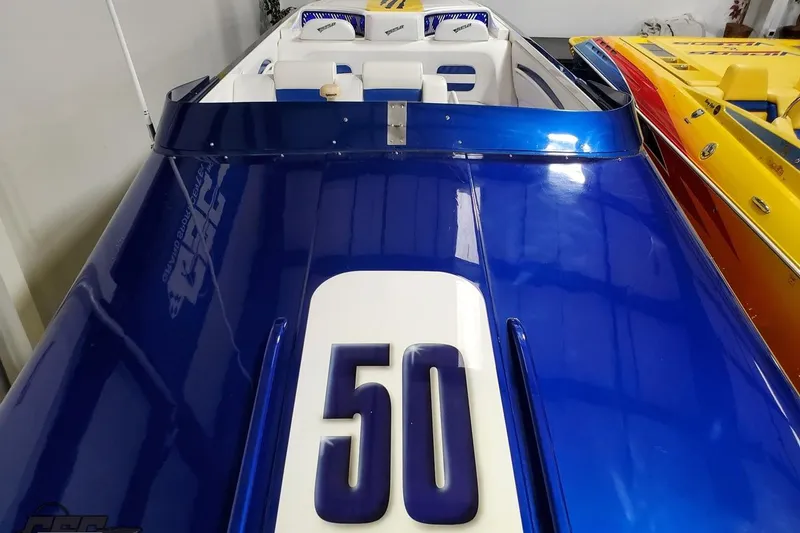 Slide: The Image of Blue 2001 Hustler 50 Monster speedboat with white interior, docked alongside a yellow boat. - 26