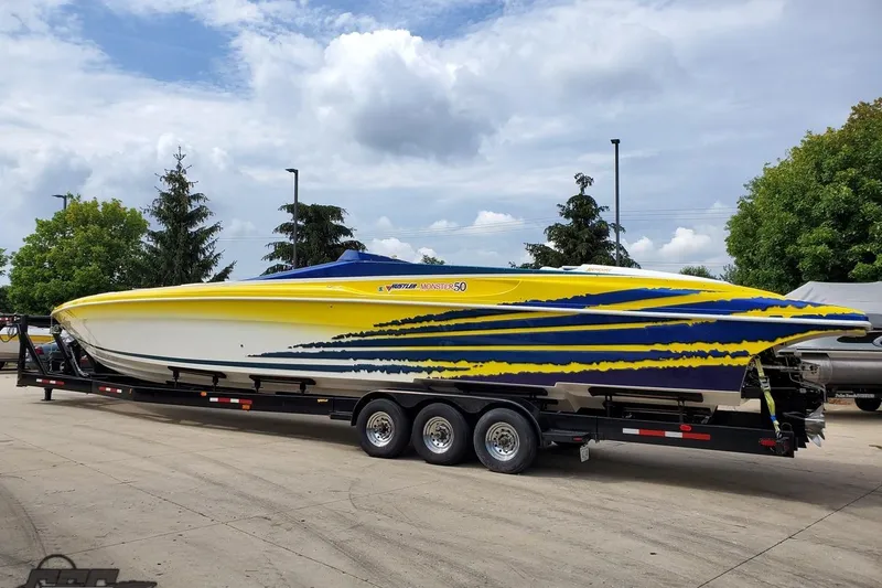 Slide: The Image of 2001 Hustler 50 Monster speedboat with vibrant yellow and blue design on a trailer. - 4