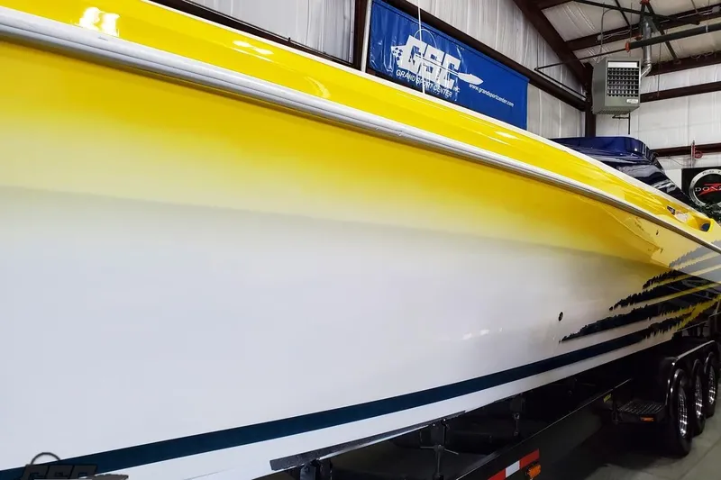 Slide: The Image of 2001 Hustler 50 Monster boat with yellow and white gradient hull in a garage setting. - 5