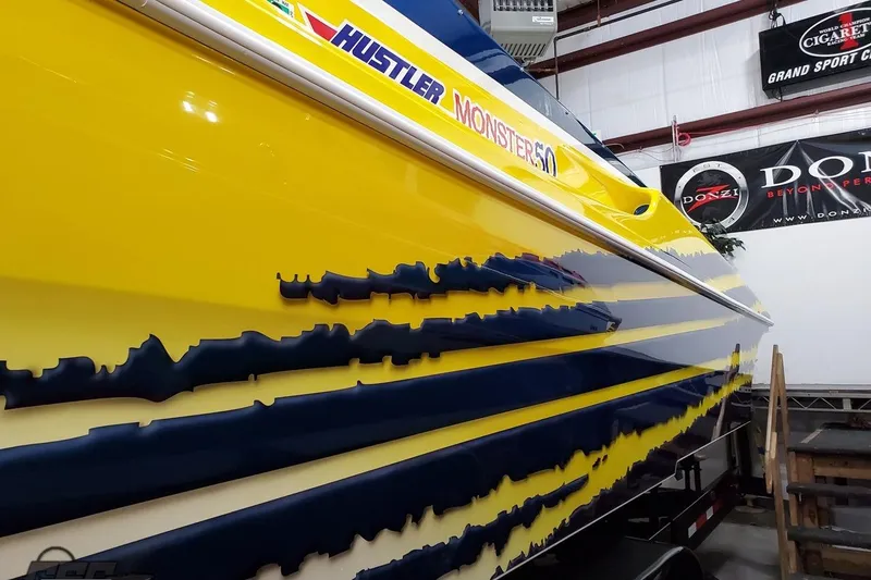 Slide: The Image of Yellow and blue 2001 Hustler 50 Monster boat with bold graphics in a showroom. - 6