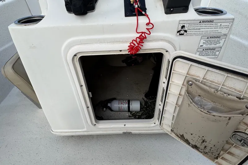 Slide: The Image of Open storage compartment on a 2016 Carolina Skiff 218 DLV boat with safety equipment. - 14