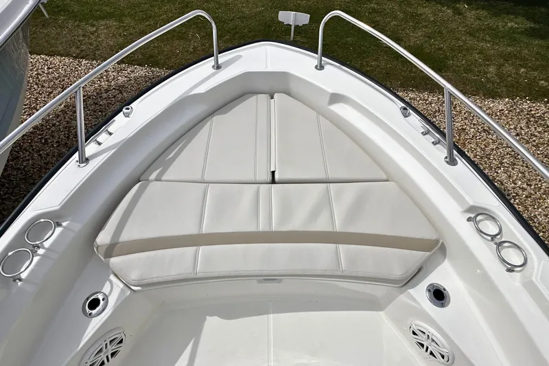 Slide: The Image of Bow seating area of 2026 Boston Whaler 220 Dauntless with white cushions and stainless steel railings. - 14