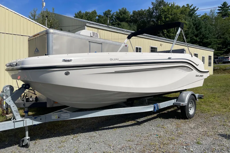 The Image of 2024 Bayliner DX 2050 boat on trailer, parked outdoors near a building. - 0