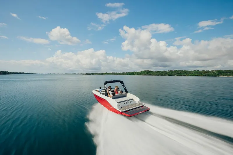 Slide: The Image of 2024 Bayliner DX 2050 speeding on a serene lake under a clear blue sky. - 6