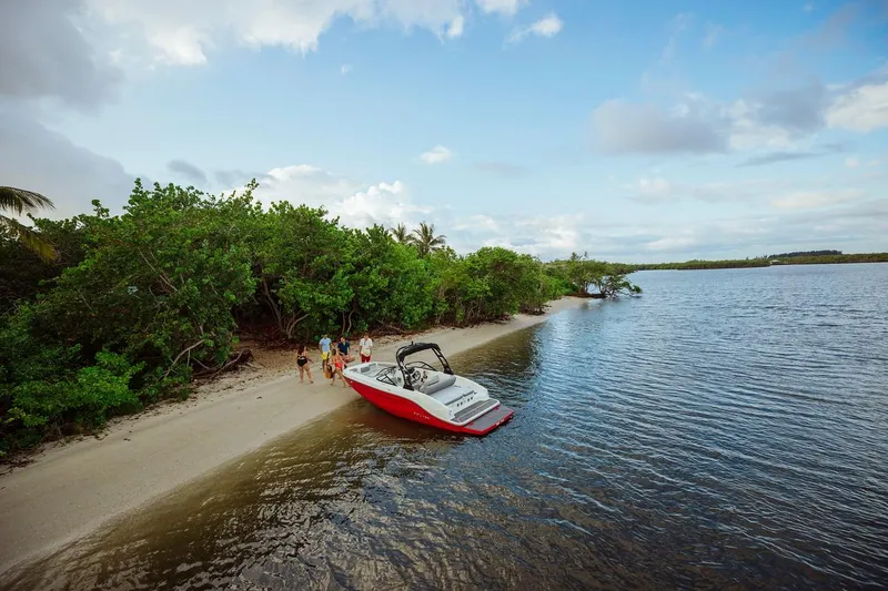 Slide: The Image of 2024 Bayliner DX 2050 boat docked on a scenic beach with lush greenery. - 9