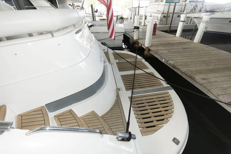 Slide: The Image of 2001 Neptunus 56 Express yacht docked, featuring sleek design and wooden deck details. - 10