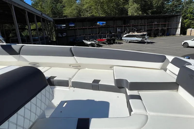 Slide: The Image of 2024 Bayliner DX 2000 boat interior with spacious seating in a marina setting. - 10