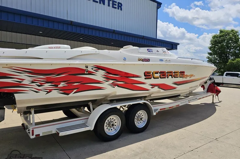 Slide: The Image of 2001 Wellcraft 33 Scarab AVS boat with vibrant red graphics on a trailer. - 11