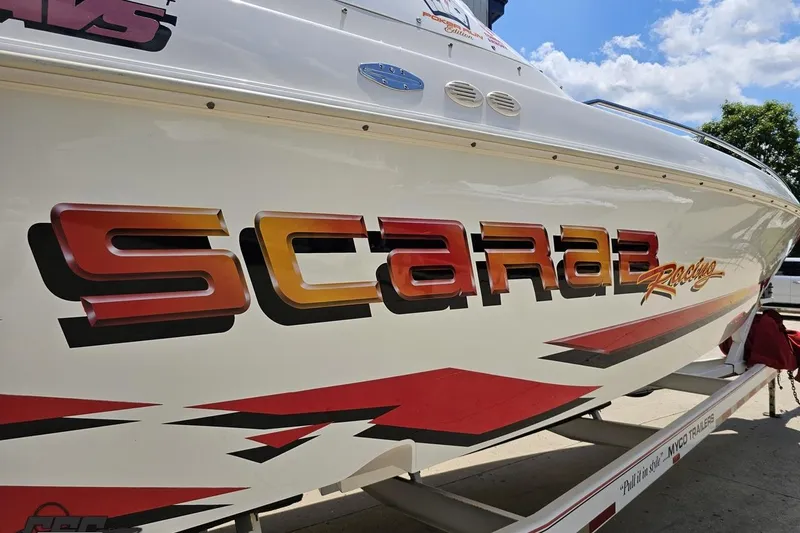 Slide: The Image of 2001 Wellcraft 33 Scarab AVS boat with bold racing graphics and vibrant colors. - 12