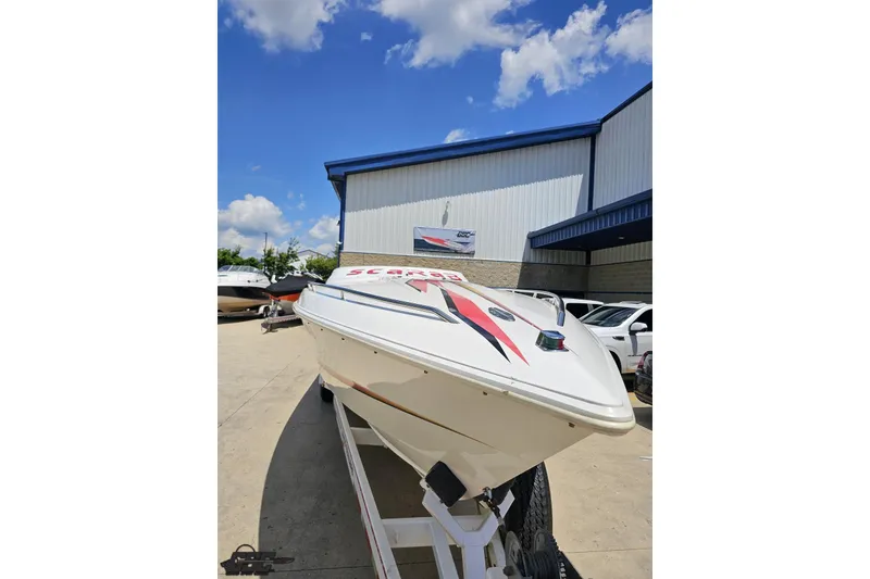 Slide: The Image of 2001 Wellcraft 33 Scarab AVS boat on trailer, parked outside a building under blue sky. - 15