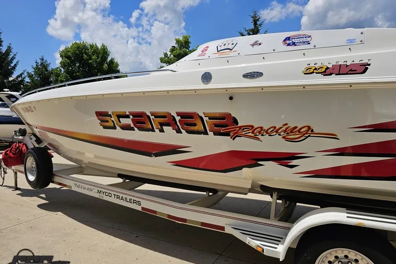 Slide: The Image of 2001 Wellcraft 33 Scarab AVS boat on trailer, vibrant racing graphics, sunny day. - 25