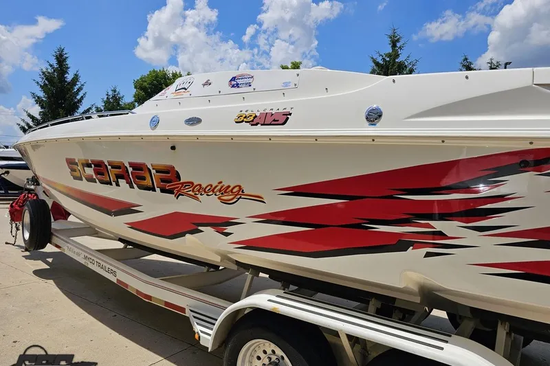 Slide: The Image of 2001 Wellcraft 33 Scarab AVS boat with vibrant racing graphics on a trailer. - 26