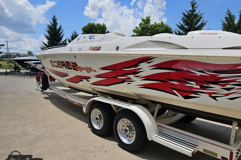 Slide: The Image of 2001 Wellcraft 33 Scarab AVS boat with vibrant red graphics on a trailer. - 27