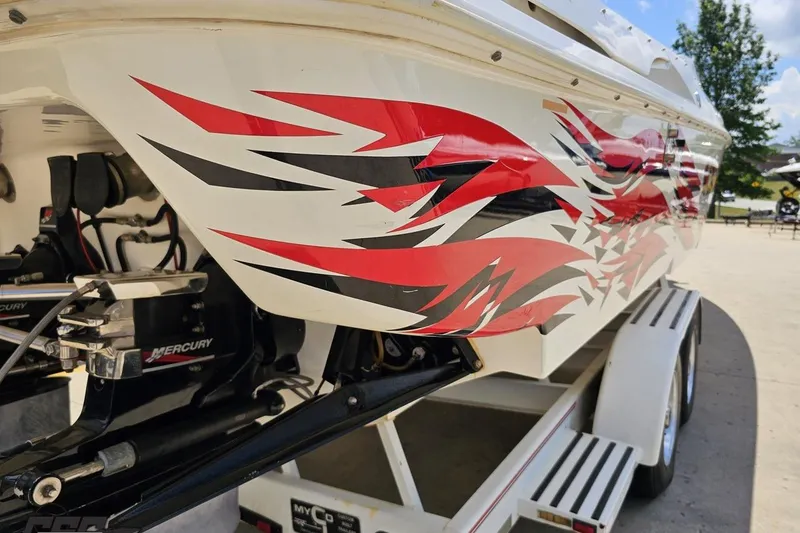 Slide: The Image of 2001 Wellcraft 33 Scarab AVS boat with vibrant red and black graphics on trailer. - 36