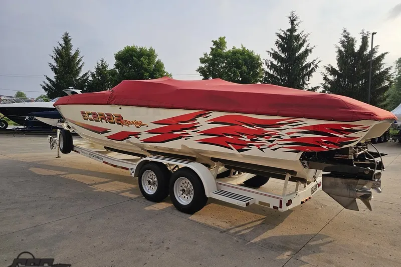 Slide: The Image of 2001 Wellcraft 33 Scarab AVS boat with red cover on trailer, vibrant graphics. - 39