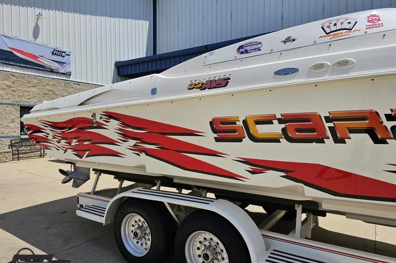 Slide: The Image of 2001 Wellcraft 33 Scarab AVS boat with vibrant red graphics on a trailer. - 6