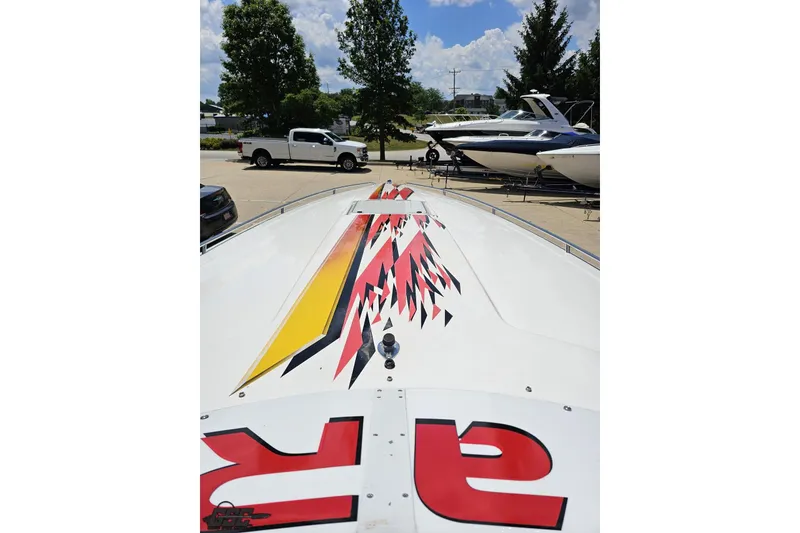 Slide: The Image of 2001 Wellcraft 33 Scarab AVS boat with vibrant graphics, parked outdoors. - 65