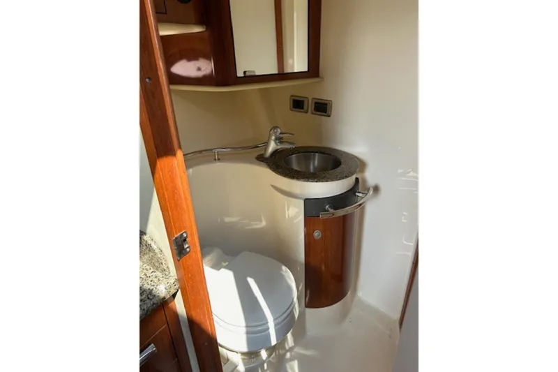 Slide: The Image of 2005 Sea Ray 390 Sundancer bathroom with sink and toilet, featuring wood accents. - 14