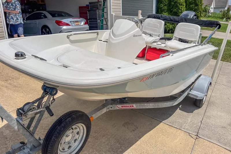 Slide: The Image of 2016 Boston Whaler 130 Super Sport boat on trailer in driveway. - 5