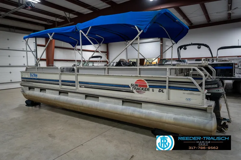 Slide: The Image of 1992 Sun Tracker Party Barge 24 pontoon boat with blue canopy in indoor storage. - 10