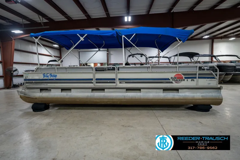 Slide: The Image of 1992 Sun Tracker Party Barge 24 pontoon boat with blue canopy in indoor storage. - 11