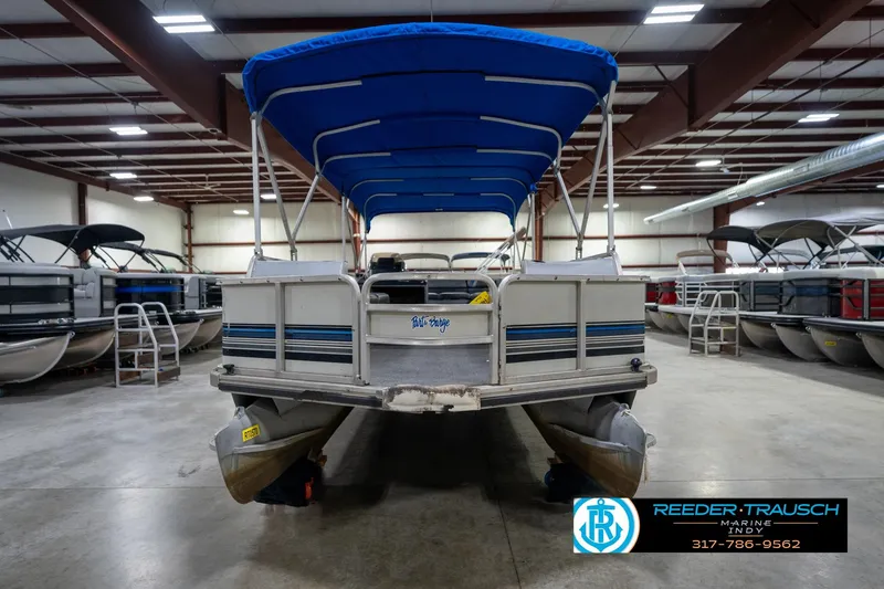 Slide: The Image of 1992 Sun Tracker Party Barge 24 pontoon boat with blue canopy in indoor storage. - 5