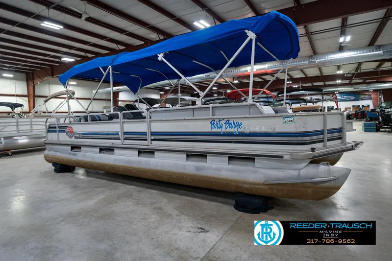 Slide: The Image of 1992 Sun Tracker Party Barge 24 pontoon boat with blue canopy in indoor storage. - 6