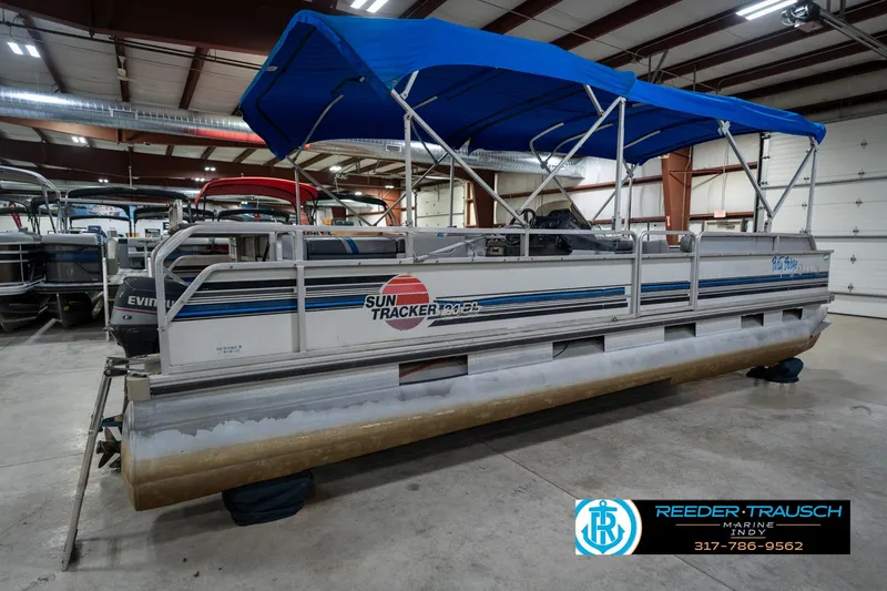 Slide: The Image of 1992 Sun Tracker Party Barge 24 pontoon boat with blue canopy in indoor showroom. - 8