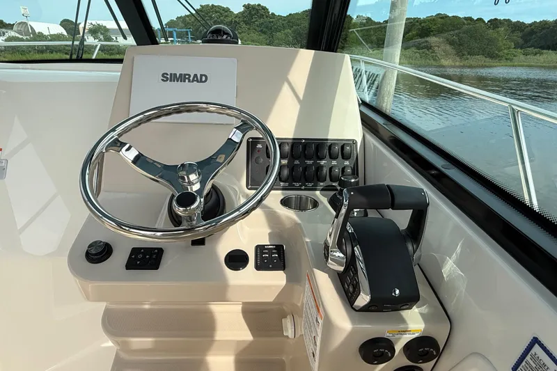 Slide: The Image of 2026 Boston Whaler 285 Conquest helm with Simrad electronics and sleek steering wheel. - 23