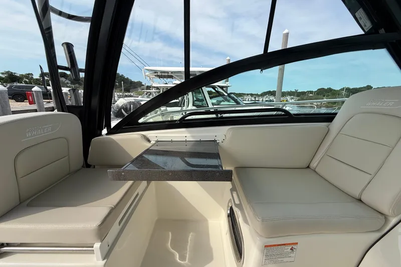 Slide: The Image of 2026 Boston Whaler 285 Conquest interior with seating and table, docked at marina. - 26
