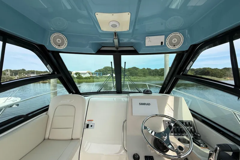 Slide: The Image of 2026 Boston Whaler 285 Conquest helm with Simrad electronics, overlooking serene waters. - 27
